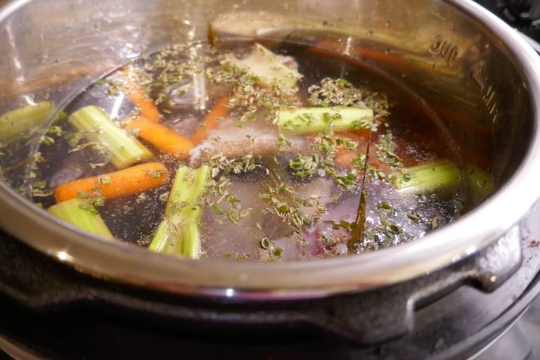 a large cooking pot filled with fish parts and vegetables to make broth